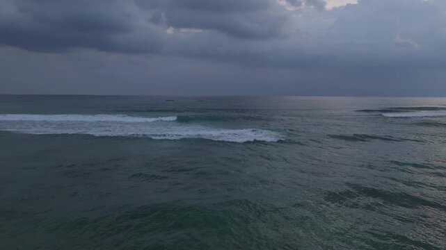 Aerial wide view of open ocean with rolling waves and textured water beneath heavy clouds