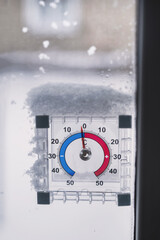 Naklejka premium The thermometer shows -10 degrees Celsius, frost and snow in winter, subzero temperatures outside. Condensation on windows, home insulation, how to survive the cold and fix your heating. vertical