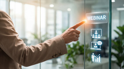 Professional pointing to holographic WEBINAR button on transparent glass in office. Concept of digital education, virtual business training, and remote corporate communication strategy.