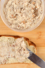 Top view of traditional minced lard spread known as zaseka being applied to a slice of fresh bread on a wooden surface