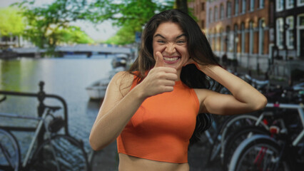 Naklejka premium Woman gives thumbs up gesture on street by building; approval optimism confidence positivity.
