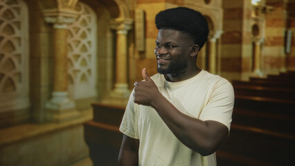 Obraz premium Man giving thumbs up with visible hand inside catholic church nave smiling toward camera; faith approval joy.