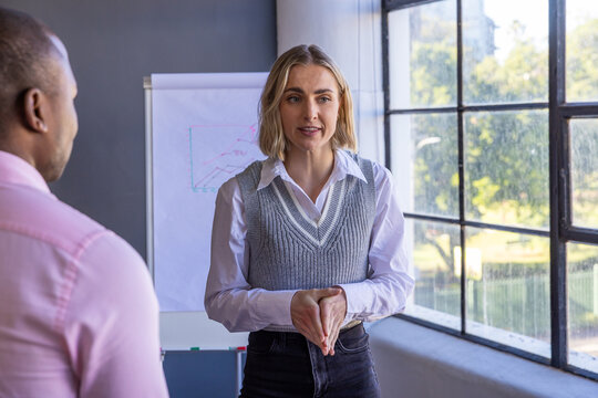 Diverse colleagues presenting data on flip chart with markers in meeting room - Powered by Adobe
