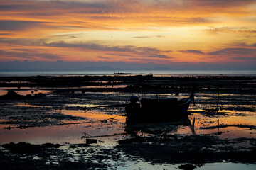 Silhouette long tail boat parking on the beach in the morning with sunrise sky and horizontal line in background