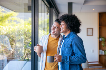 Two men holding ceramic mugs and gazing through floor-to-ceiling glass door in modern living room