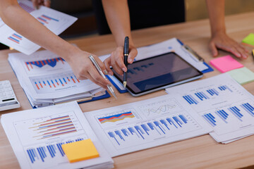 Group of confident business people point to graphs and charts to analyze market data, balance...