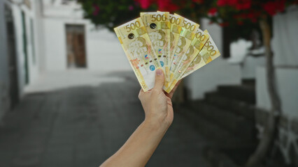 Caucasian man holding philippine peso banknotes on a city street with blurred background and urban...