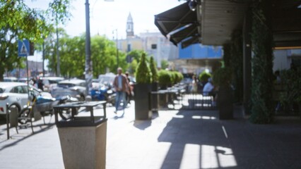 Obraz premium Sunlit urban sidewalk cafe scene softly defocused with shallow bokeh street; background backdrop copyspace calm.