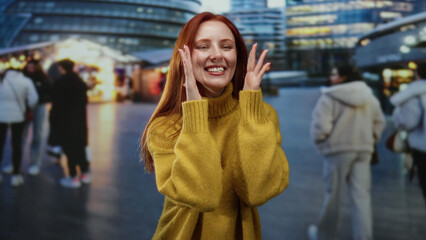 Fototapeta premium Woman laughing on a bustling city street at night, wearing yellow sweater, surrounded by blurred urban lights and people, conveying a joyful and vibrant scene outdoors.