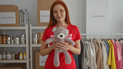 Woman holding teddy bear in donation center with red shirt surrounded by clothes and canned goods illustrating charity work indoors