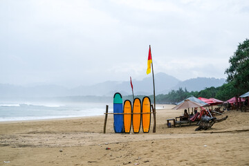 Surf training and board rental spot at Pulau Merah Beach, Banyuwangi, featuring colorful surfboards on sand, gentle waves for beginners, and an international surfing atmosphere.