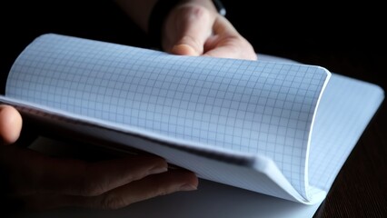 Female hands Flipping new notebook pages. Fast flicking of paper checkered sheets. View browsing. Search of note. Pleasant tactile sensations and stress relief. High quality photo