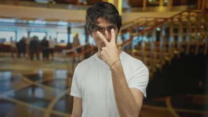 Man in white shirt points finger to chest on polished marble floor in hotel lobby near spiral staircase; skepticism doubt.