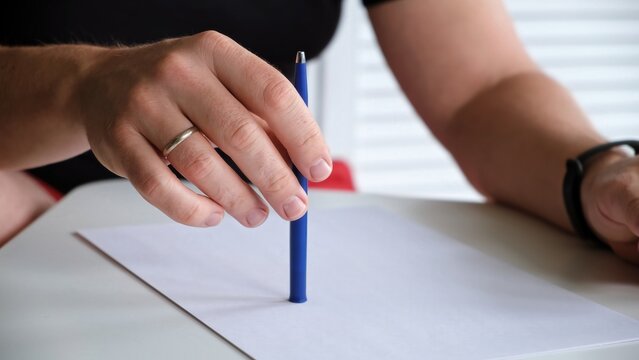 A man tapping a pen on a table with a blank sheet of paper. The concept of lack of ideas, problems, nervous state, lack of inspiration. Beat the rhythm of the melody. Music teacher. High quality