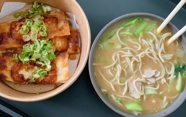 Asian Comfort Food Meal with Noodle Soup and Crispy Spring Rolls; Hot Asian Noodle Soup Served with Fried Spring Rolls