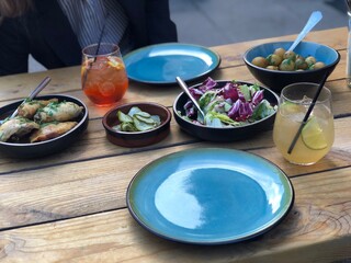Traditional Danish Bistro Meal with Shared Dishes and Refreshing Drinks; Scandinavian Bistro Table; fresh salads, roasted meat, and refreshing drinks on a rustic wooden table