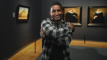Young black man offering hug with outstretched hands amid framed paintings in museum building; warmth joy.
