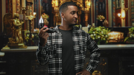 Obraz premium Man holding electric screwdriver with hand raised pointing tool toward ornate altar in church interior, wearing plaid shirt and casual pose; quiet contemplation.