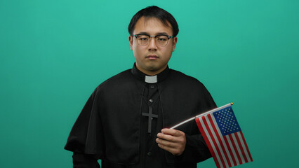 Priest holding american flag with young man against green background pointing confidently suggesting a religious and cultural discussion in usa context