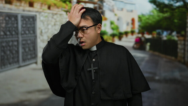 Young man wearing a clerical collar stands outdoors in an urban setting, looking pensive and thoughtful amid a city backdrop, suggesting contemplation and introspection.
