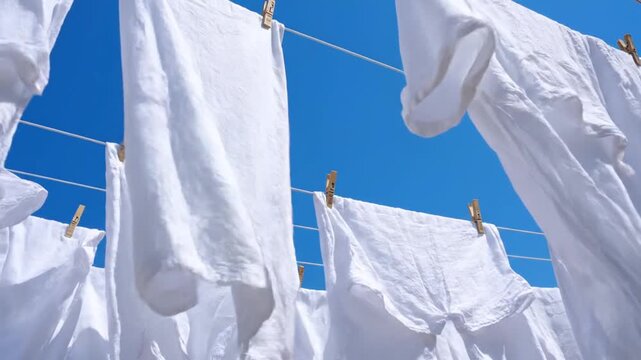 White clothes drying on a clothesline against a clear blue sky, viewed from below, Untitled video file (22).mp4 reference