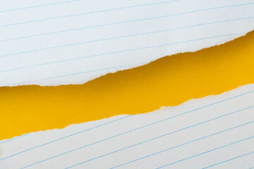 uneven torn white lined paper on grunge yellow paper, top view