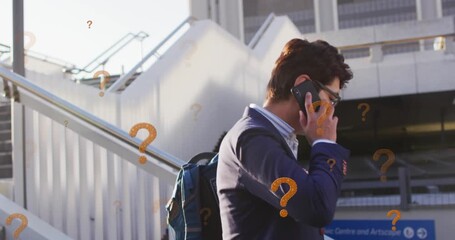 Animation of question marks over asian businessman talking on smartphone - Powered by Adobe