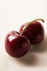 Obraz premium Two Fresh Dark Red Cherries with Water Droplets on Neutral Background