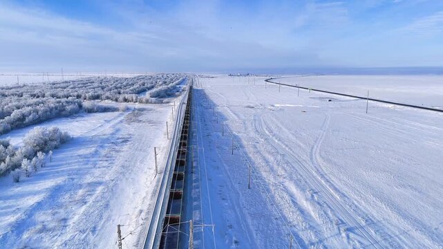 a train with empty carriages is traveling on a winter railway, with trees covered in white frost