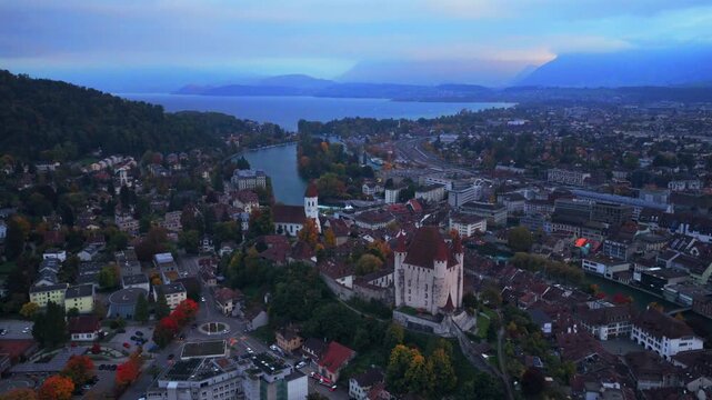 Thun Castle Flusswelle Aare River aerial drone view Schloss Thun Thunersee Switzerland Schweiz Europe Autumn Fall morning grey skies buildings yellow birches tree Bernese Oberland circle right motion