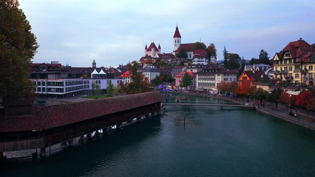 Thun Castle Flusswelle Aare River Schloss Thun Thunersee Switzerland Schweiz Europe Autumn Fall aerial drone morning grey skies yellow birches tree pedestrian walkway Bernese Oberland upwards pan down