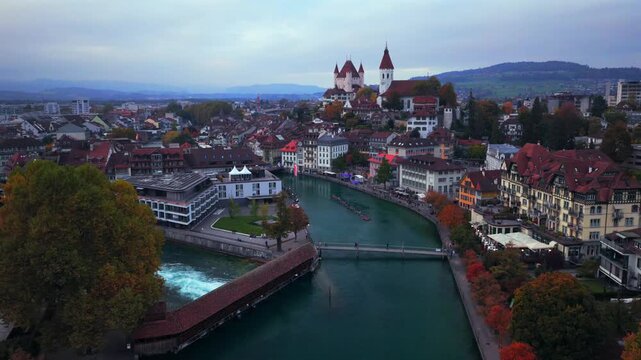 Thun Castle Flusswelle Aare River Schloss Thun Thunersee Switzerland Schweiz Europe Autumn Fall aerial drone morning grey skies yellow birches tree pedestrian walkway Bernese Oberland forwards pan up