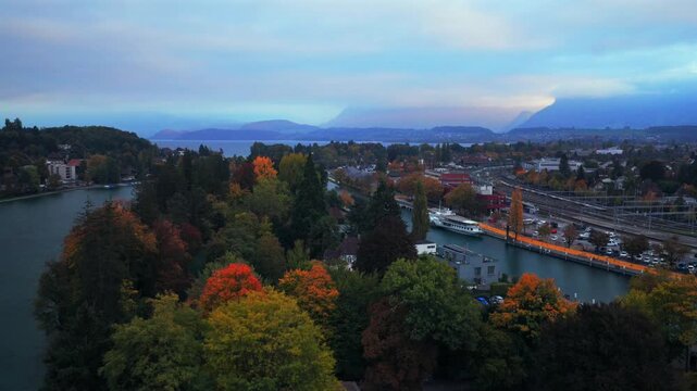 Thunersee Lake Thun Flusswelle Aare River Ferry aerial drone Thun Switzerland Schweiz Fall Autumn morning clouds Swiss Alps Grindelwald Jungfrau mountains Bernese Oberland Interlaken upwards motion