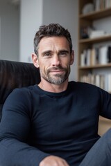 Confident middle aged male psychologist consultant sitting in office looking at camera. Mature professional therapist or business coach working in modern workplace. Portrait