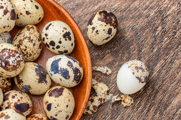 Top view of quail eggs in wooden plate on table
