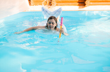 Happy child swimming in a pool with a safety ring on a bright summer day.
