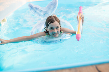 Happy child swimming in a pool with a safety ring on a bright summer day.