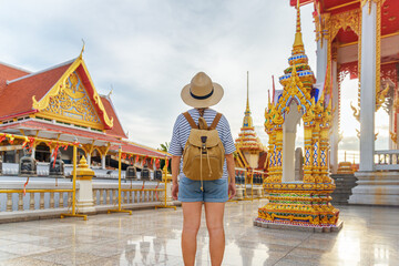 Female tourist in hat with backpack at a Buddhist temple