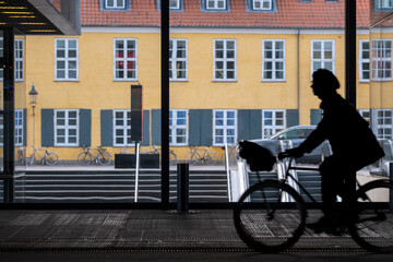 Urban street cycling bicycle commute with silhouette and shadow against architecture facade in copenhagen during bright morning movement