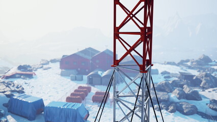 Construction activities unfold in a chilly landscape, featuring a prominent red and white tower. Colorful storage units and a collection of buildings dot the snowy terrain under bright sunlight. © icetray