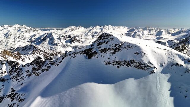 Aerial drone footage of ascent over mountain summit in the wintry European Alps