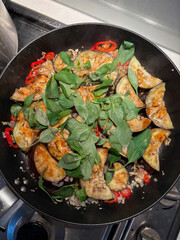 A frying pan with eggplant and thai basil leaves.