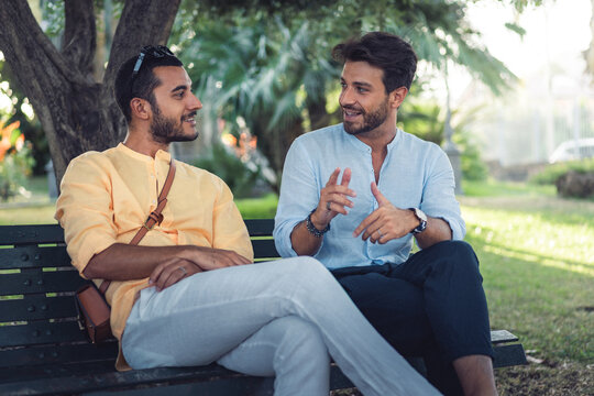 Two male friends having an engaged conversation while sitting on a park bench
