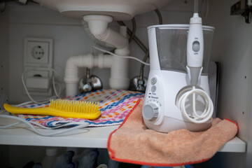 Home bathroom storage with electric oral irrigator towel and brush under sink in organized cabinet space