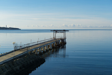 Obraz premium Waterfront scene featuring pier extending into Black sea water, against resort Gelendzhik bay, under blue sky