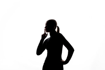 Side-profile silhouette of a woman gesturing "shh" with one finger raised to her lips, set against a bright white background with ample copy space