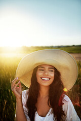 Fototapeta premium Thinking, woman and happy with hat in nature for travel, fresh air and reflection on holiday. Space, female person or vacation with vision in field, daydreaming and sightseeing outdoor in countryside