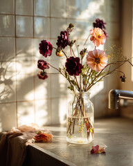 Bouquet of colorful flowers in glass vase on kitchen countertop  
