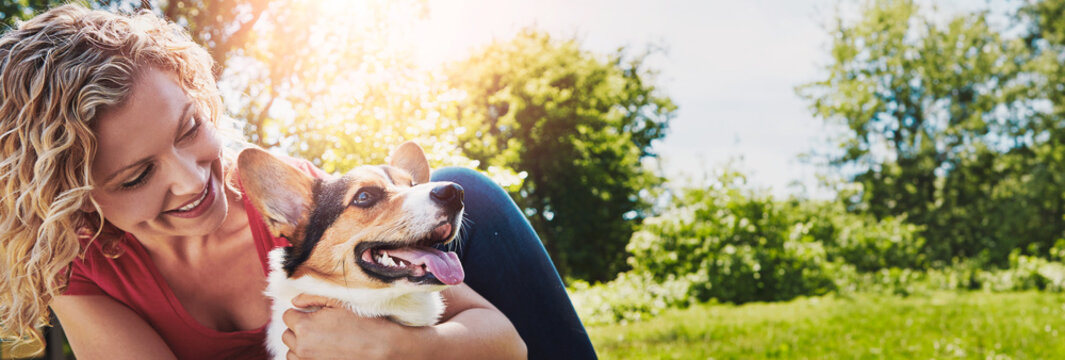 Hug, playing and woman with dog in nature for bonding, connection or adoption together. Smile, love and female person with corgi puppy, animal or pet for fun and companionship outdoor in park.