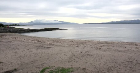 Wide panning shot of Ganavan beach and Bay with black Highland midges at Oban